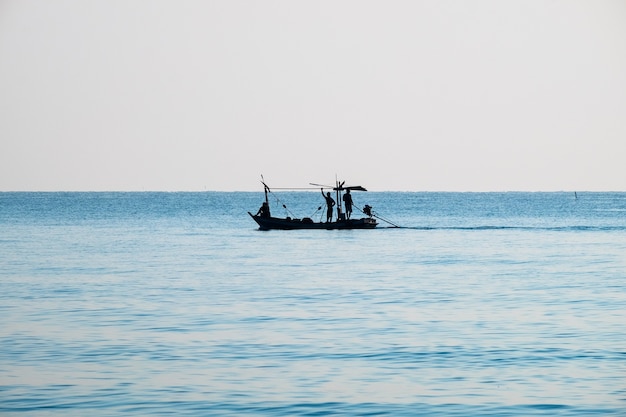 Silhouetvisser die in de ochtend blauwe zee mooi natuurlijk vist