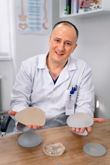 Silicone breast implant in doctors hands Smiling plastic surgeons hand with breast implant Vertical view