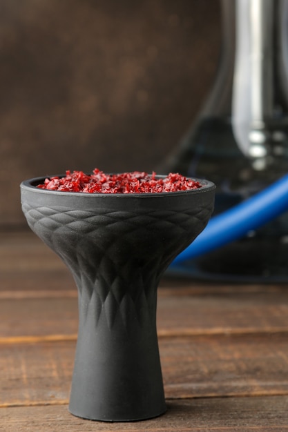 Silicone hookah bowl with tobacco on a brown wooden table. close-up. accessories for hookah.