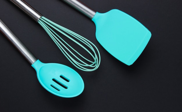 Silicone kitchen tools on a black table. Top view.