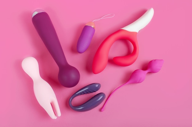 분홍색 배경에 실리콘 섹스 토이. 재미를 위한 에로틱 장난감. 섹스 가제트 및 자위 기구.