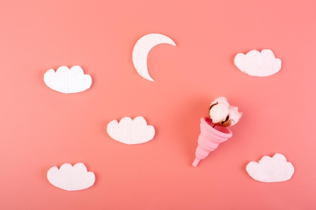 Siliconen roze menstruatiecup met maan en wolken katoen flatlay op een roze achtergrond Women's health