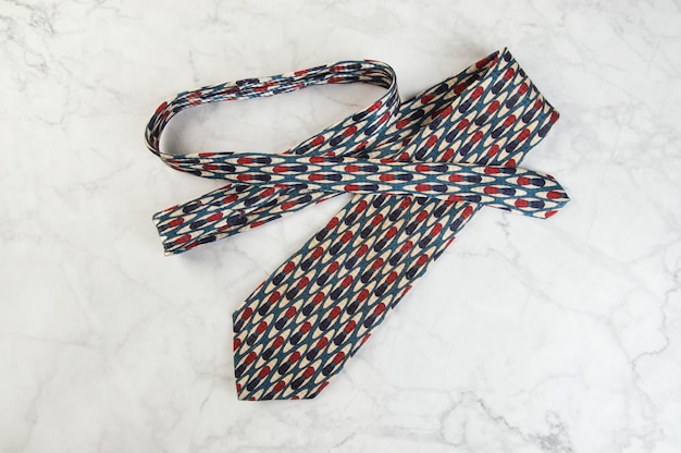 SIlk neck tie with geometric pattern on marble background. Copy space for text.