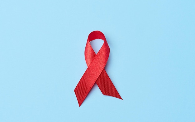 A silk red ribbon in the form of a bow on a blue background a symbol of the fight against AIDS and a sign of solidarity and support