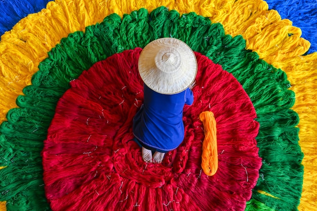 The silk weaver was preparing a roll of colorful silk threads before weaving them into cloth.