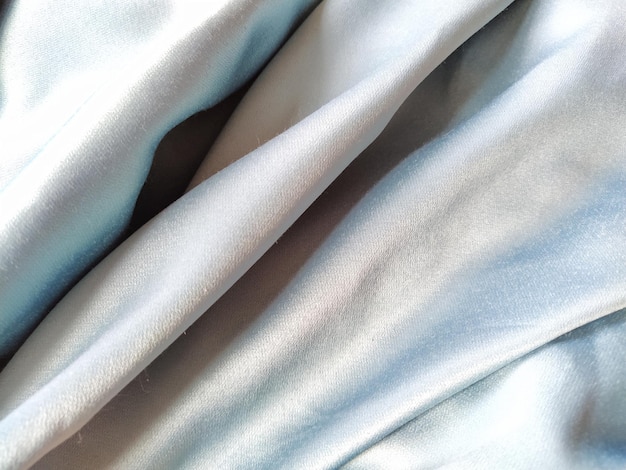 Шелковистая на ощупь ткань серо-голубого цвета с блестящим отливом Естественное освещение светотенью Материал небрежно сложен Полиэстер Текстиль
