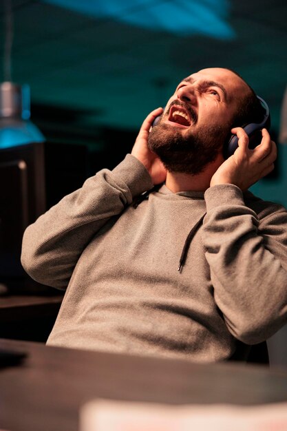 silly young coder screaming and listening to music on headset, working on app developing software late at night. web developer singing song in office, coding online cloud database.