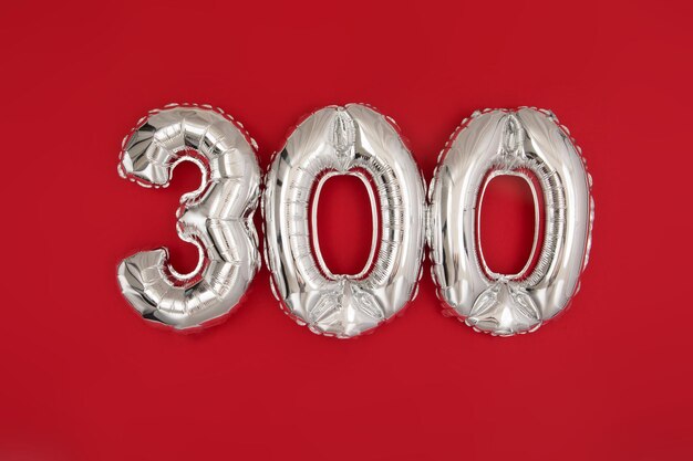 Photo silver balloon showing number 300 on red background