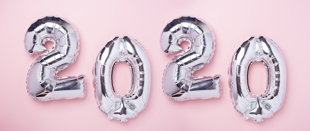 Silver balloons in the form of numbers 2020 on pink 