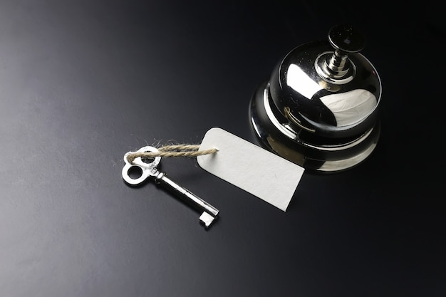 Photo silver bell and the key at the reception in the hotel on a black background