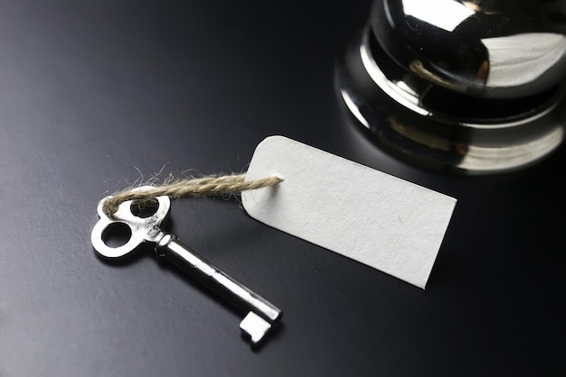 Silver bell and the key at the reception in the hotel on a black background