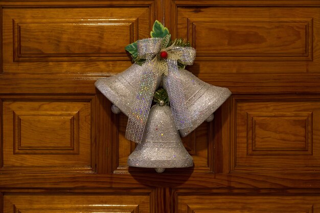 写真 木製のドアの入り口にぶら下がっている銀の鐘クリスマスシーズンは自宅で花輪を飾ります