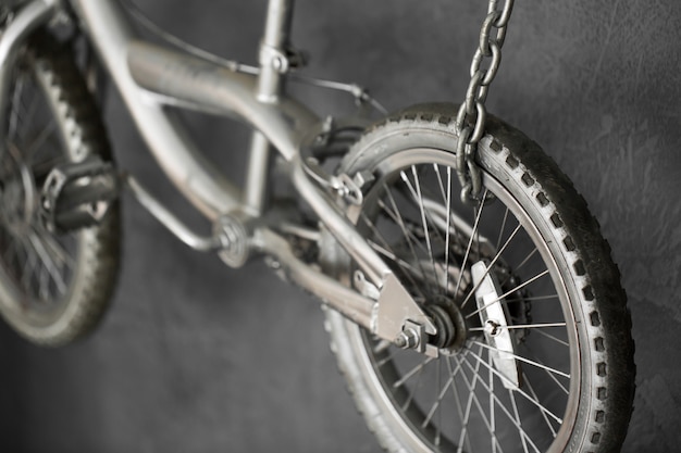 Silver bike hanging on chains against the wall in the studio