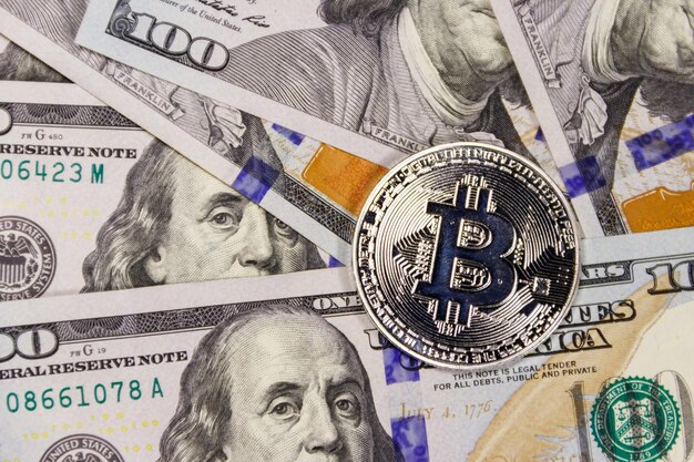 Silver bitcoin on hundred dollar bills background