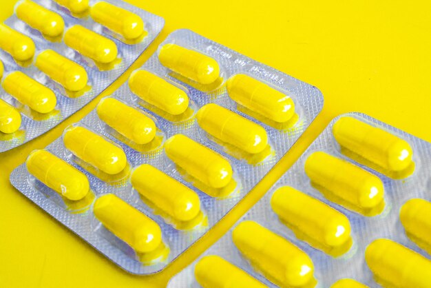 A silver blister packs full of pills on a yellow background