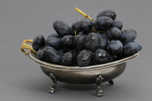 A silver bowl of grapes with the word grapes on it.