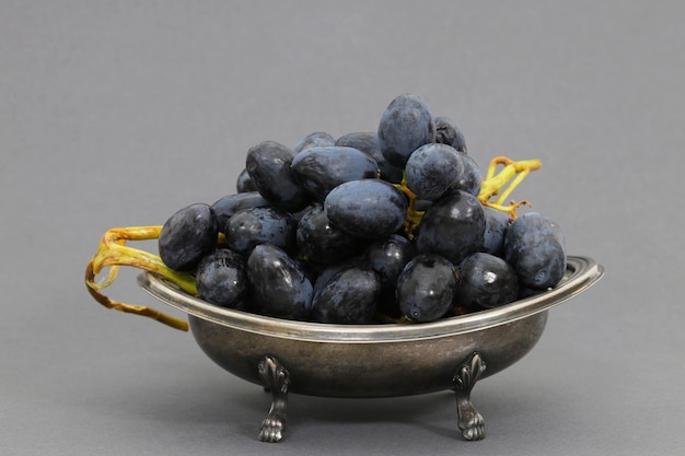 A silver bowl of grapes with the word grapes on it
