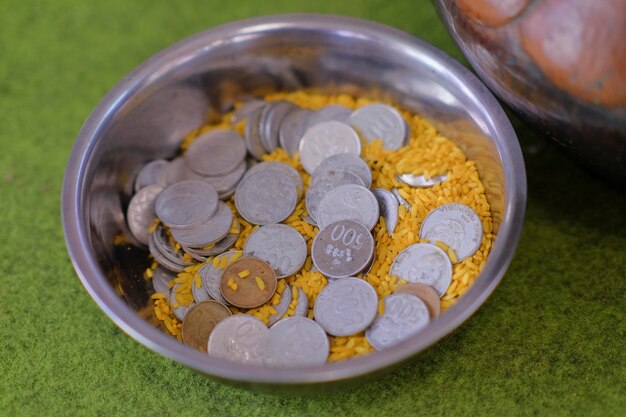 A silver bowl with coins and a silver coin with the number 00 on it.