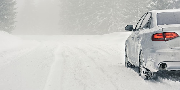 雪に覆われた道路に駐車した氷で覆われた銀色の車、後ろからの詳細ビュー、テキスト左側の背景の空きスペース