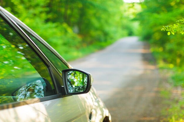 Silver car standing on the roadside of the road in the woods. Side view