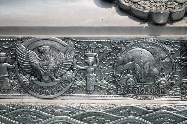 A silver carving of a buffalo and a woman with a goat on it.