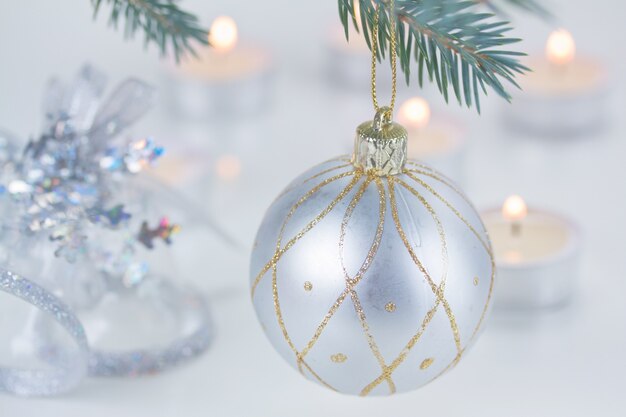 Silver  christmas ball hanging on fir tree and candle lights defocused background