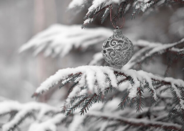 Silver Christmas ball on a natural tree in a snowy forest