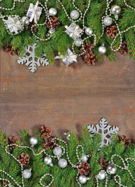 Silver Christmas decorations and spruce branch and cones on a wooden background