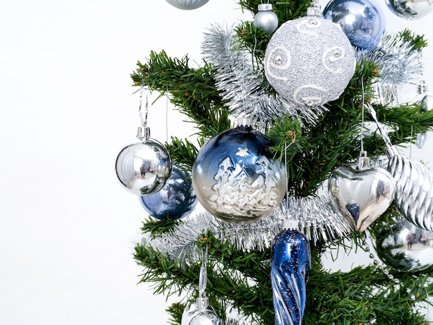 Silver Christmas decorations on a spruce branch on a white 