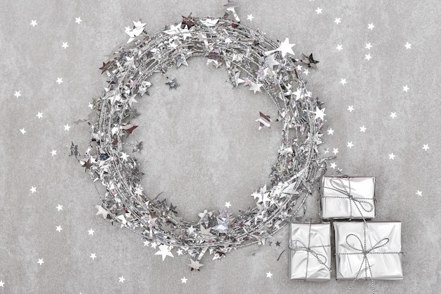 Silver christmas wreath with three gifts on a gray background. festive pattern.