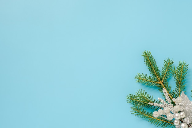 Silver color christmas decoration on green fir branch on blue background. Concept Merry christmas or Happy new year. 