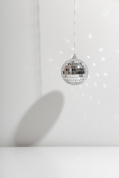 Silver disco ball reflects sunlight on silver background with shadow copyspace