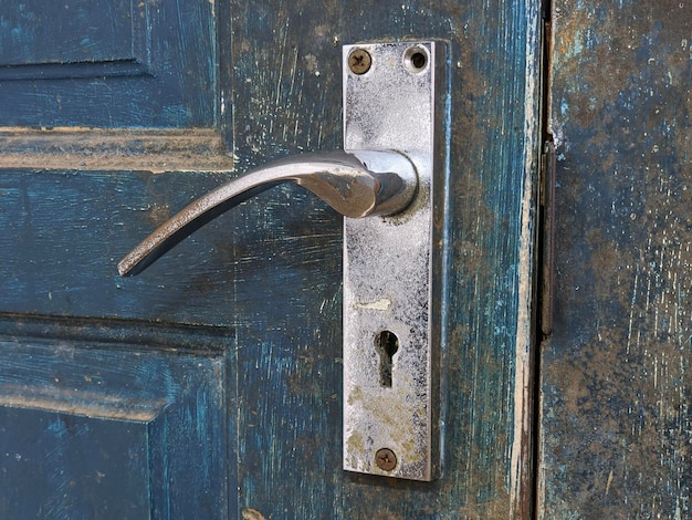 A silver door handle on blue door