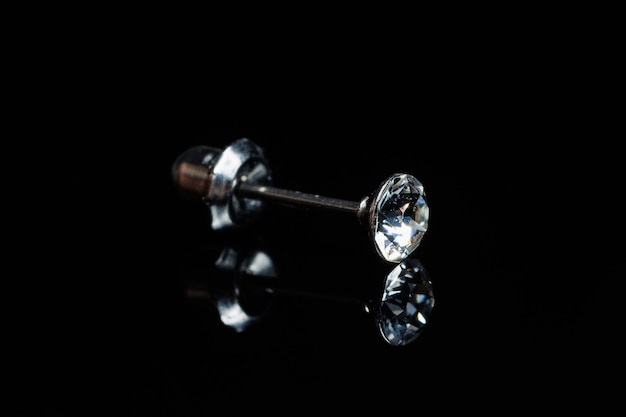 Silver earring macro photo with a precious stone on a black isolated background