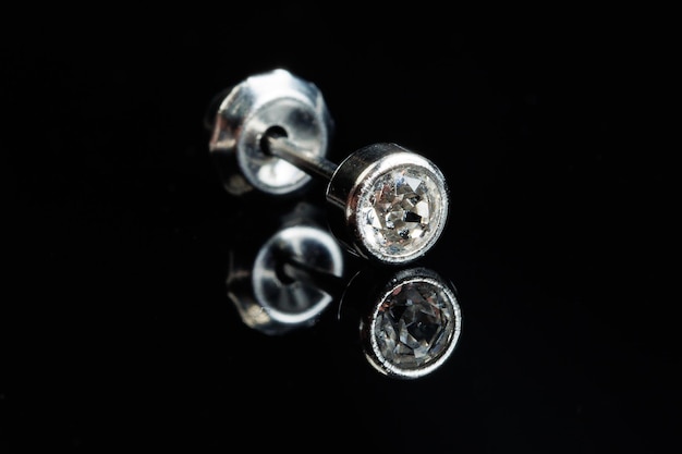 Silver earring macro photo with a precious stone on a black isolated background