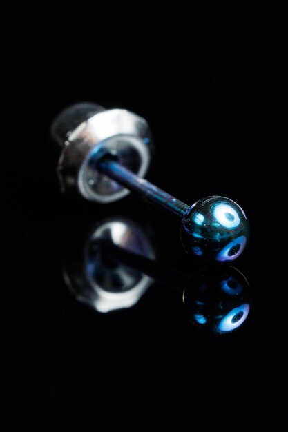 Silver earring macro photo with a precious stone on a black isolated background