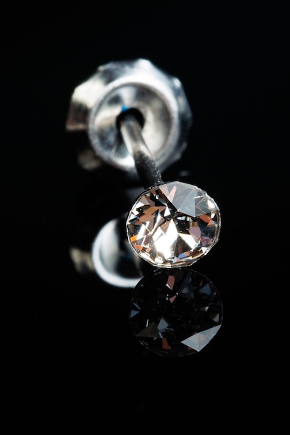 Silver earring macro photo with a precious stone on a black isolated background