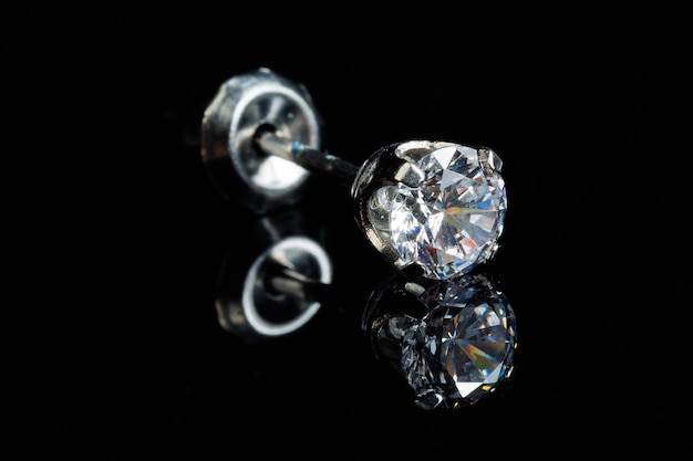 Silver earring macro photo with a precious stone on a black isolated background