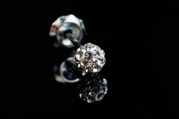 Foto macro di orecchini d'argento con una pietra preziosa su sfondo nero isolato