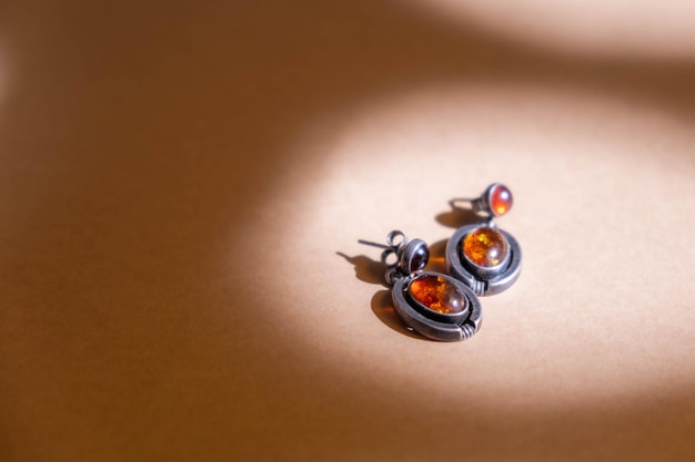 Silver earrings with amber on soft brown background.