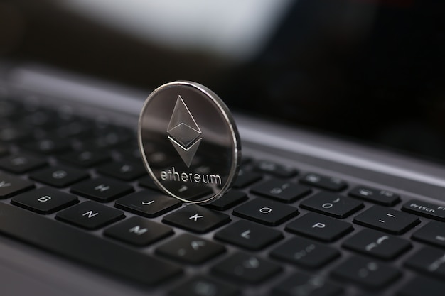 Фото Серебряная монета эфириум лежит на ноутбуке