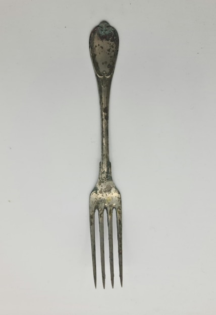 Photo a silver fork with a floral design on the bottom.