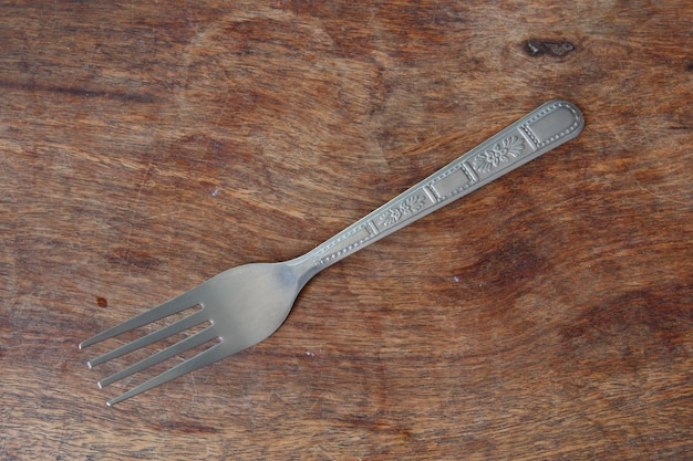 Photo silver fork on wooden background