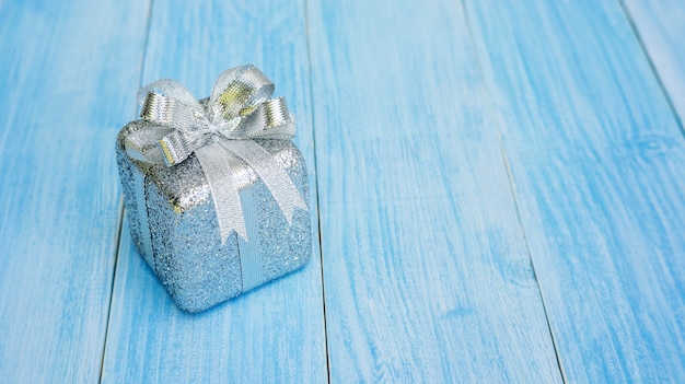 silver gift box on a blue wooden table.