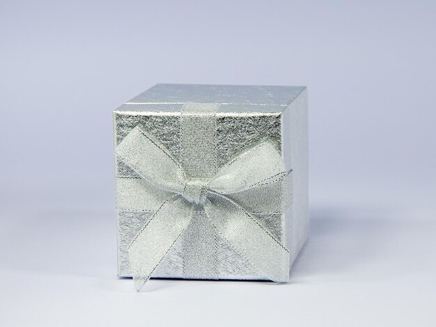 silver gift box with a bow lying on its side with the lid on the front