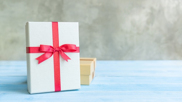 Silver and gold gift box on a blue wooden table.