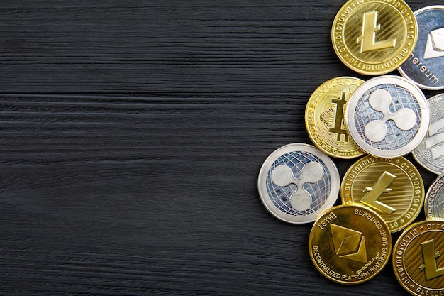 Monete d'argento e d'oro con bitcoin, ripple ed ethereum simbolo su uno sfondo di legno.