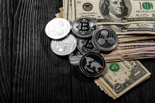 Silver and golden coins with bitcoin, ripple and ethereum symbol on wood.