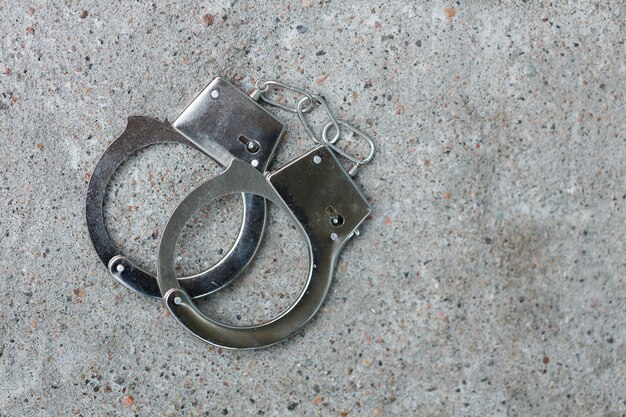 Silver handcuffs lie on the concrete floor. top view. High quality photo