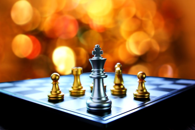 Silver king chess on chess board with multi color bokeh pattern abstract background